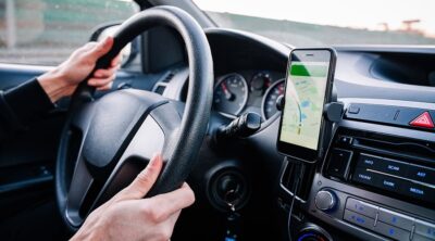 A person in a car looking for directions on a mounted phone GPS app.