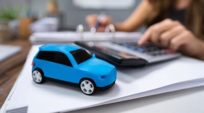 A toy car and calculator sitting on a binder full of documents.