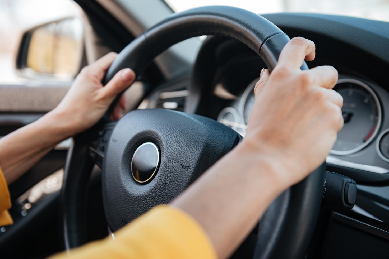 a person driving a car with their hands on the steering wheel.