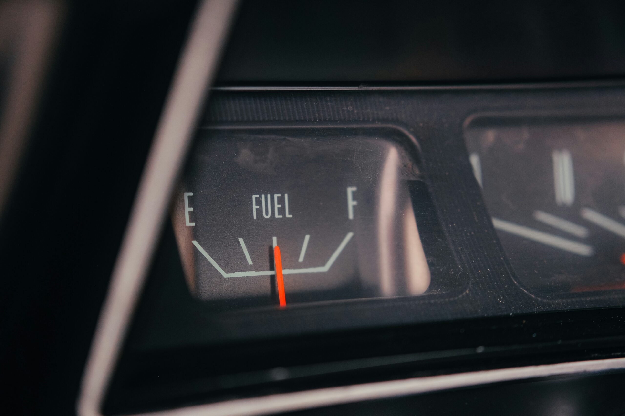 Close-up of a car dashboard fuel gauge showing the needle near empty.